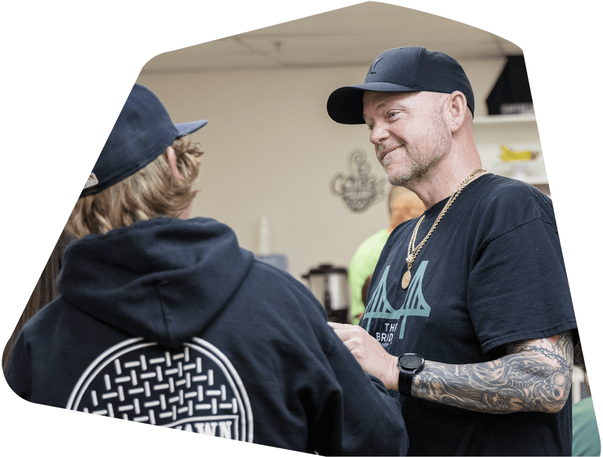 Two men shaking hands and smiling, wearing black shirts at Bridge Recovery Center